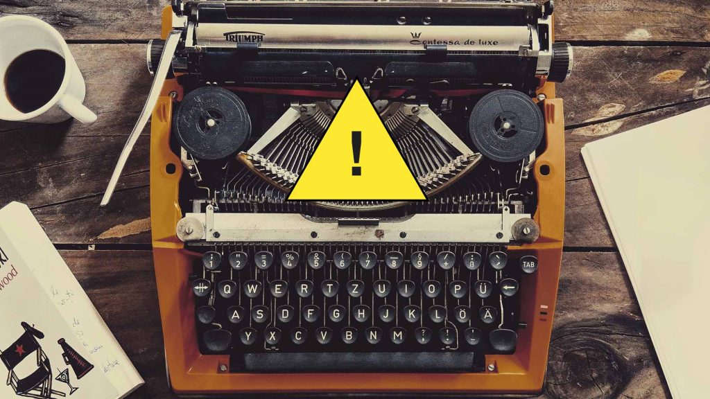 Old typewriter with warning symbol